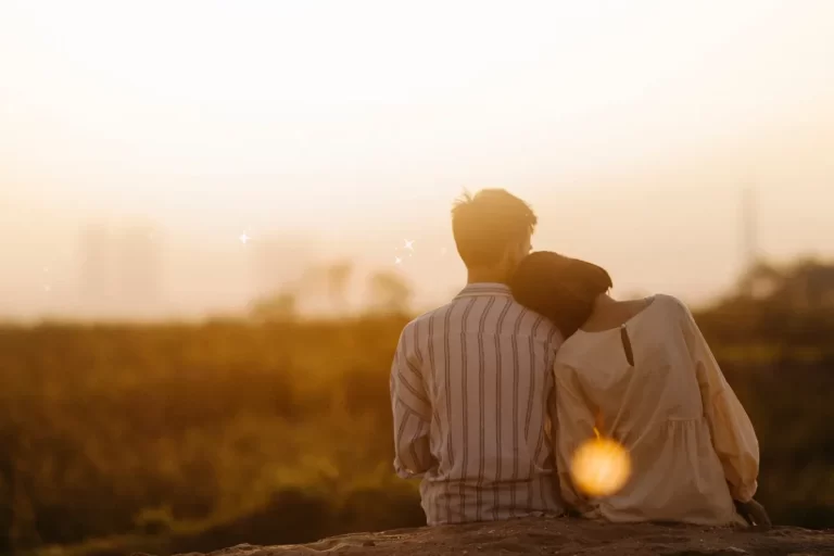 A couple gazed upon the sunset, and the woman rested her head upon her partner's shoulder.