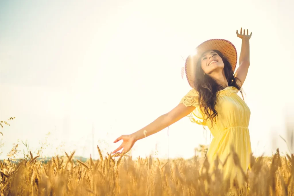 a beautiful woman smiling under the sun in wheat field