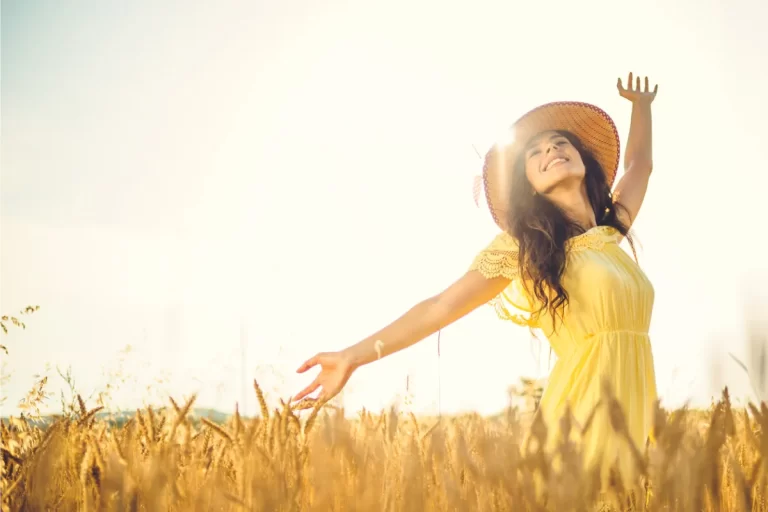a beautiful woman smiling under the sun in wheat field